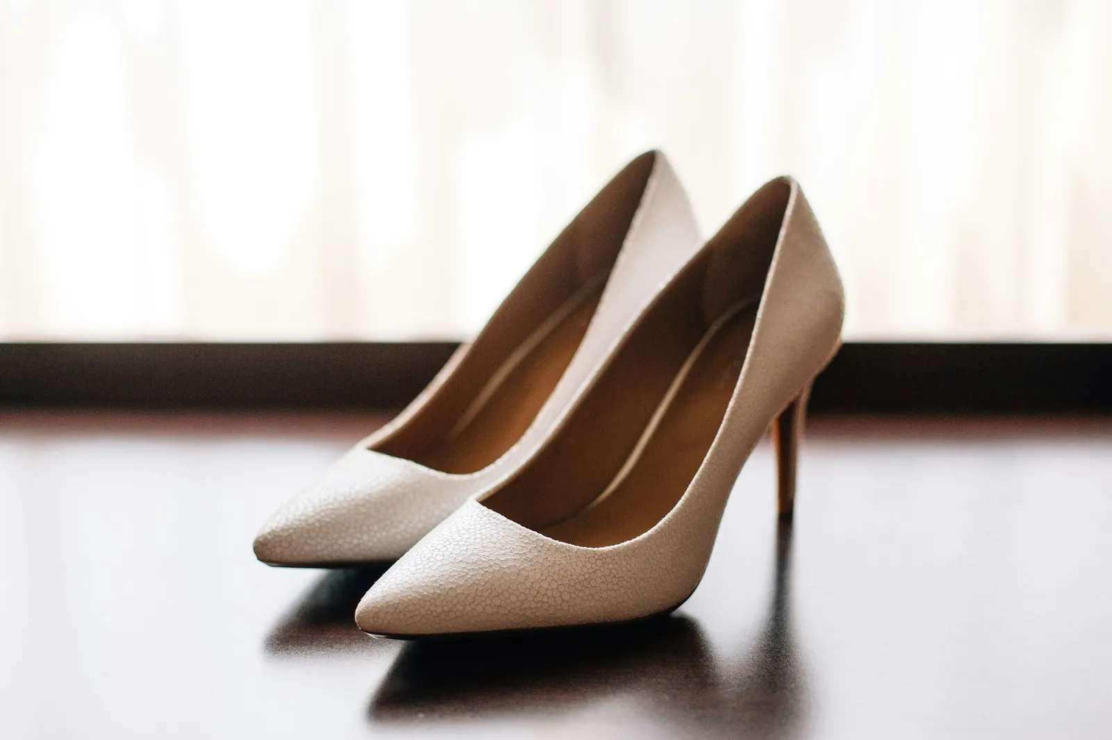 A pair of nude bridal heels in soft window light